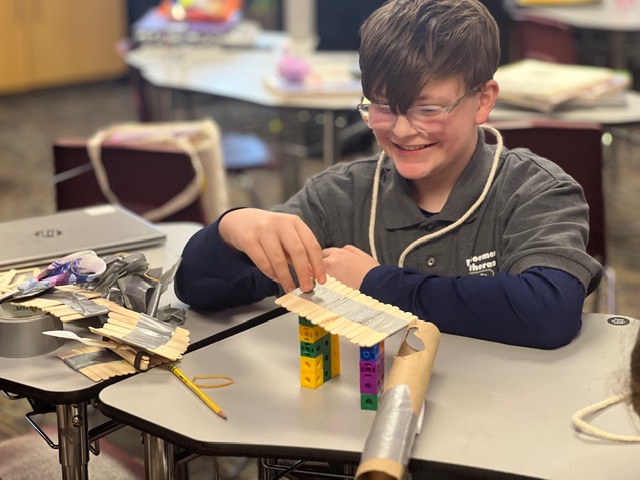Boy smiling while building with craft sticks and blocks at Redeemer Lutheran School