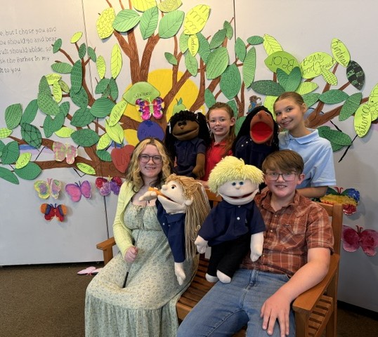 Students and puppets in front of a tree mural at Redeemer Lutheran School