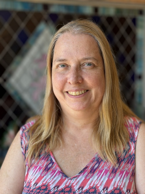 Deborah Zimmerman, smiling woman with blonde hair in a colorful top.