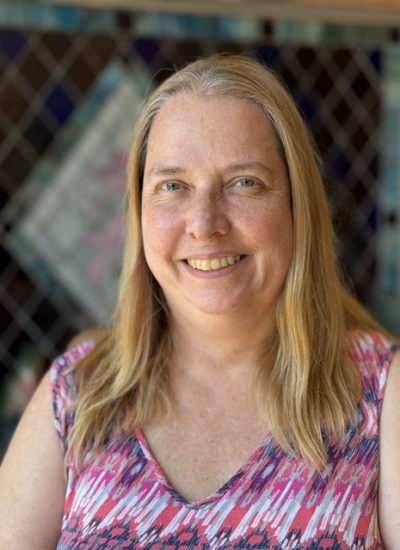 Deborah Zimmerman, smiling woman with blonde hair in a colorful top.