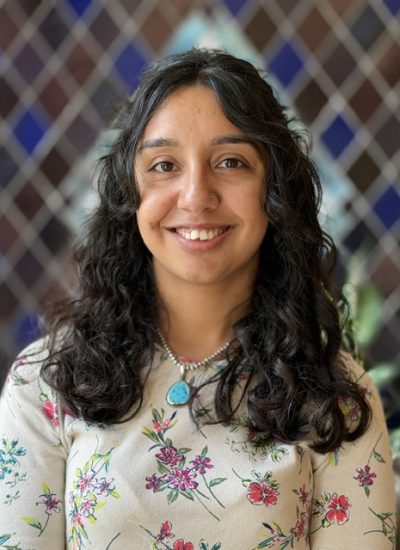 Maria Hickman, smiling woman with curly dark hair and floral shirt