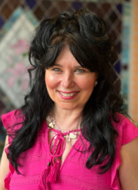 JoAnn Dellenger smiles in a bright pink top.