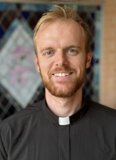 Stephen Peeler, a smiling pastor in a black clerical shirt with a white collar.